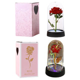 Gold foil rose glowing warm yellow under a glass dome on a wooden surface