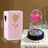 Pink foil rose in a glass dome lit with purple light on a dark base
