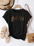 Black t-shirt with gold glitter script text graphic shown on a hanger