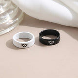 Close-up of black and white heart engraved couples rings standing upright