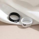 Black and white heart engraved couples rings displayed on draped satin fabric