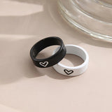 Black and white heart engraved rings leaning against a glass jar