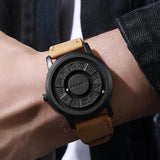 Wrist wearing black magnetic ball watch with tan strap and dark jacket sleeve