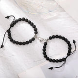 Two black matte stone bead bracelets with magnetic heart clasps on white fabric