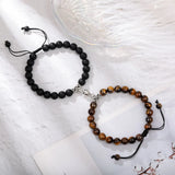 Black and tiger eye stone bead bracelet pair with magnetic clasp on white fabric