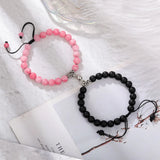 Pink and black bead bracelet pair with magnetic hearts on white fabric with flowers