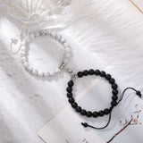 White and black stone bead bracelet pair with magnetic hearts on white fabric