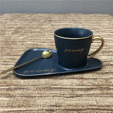 Black mug with gold script on a navy blue tray with matching saucer