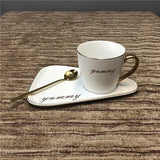 White mug with gold "yummy" script on a white tray with matching saucer