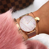 Rose gold mesh watch with pink pearl dial worn on a wrist beside pink fur