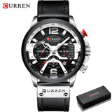 Black chronograph watch with black leather strap and red accents beside a gift box