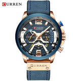 Rose gold watch with blue dial and blue leather strap next to a black gift box