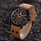 Military style watch with black dial and tan strap on a dark textured surface