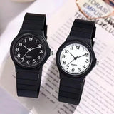 Two black resin strap watches with black and white dials resting on an open book