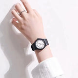 Close-up of the black resin strap watch with white dial worn on wrist