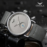 Silver case grey dial watch with gray leather strap resting on a dark surface with water drops