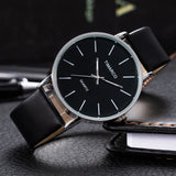 Silver case watch with black dial and black strap lying on a dark reflective surface