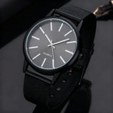 Grey dial watch with silver case and black strap on a dark reflective surface