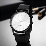 White dial watch with black strap on a dark surface with soft reflections