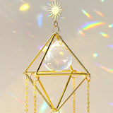 Suncatcher with gold moon and sun charms scattering rainbow prisms across a wall