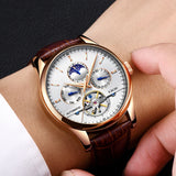Hand holding rose gold automatic moon phase watch with white dial