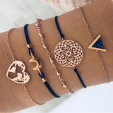 Navy cord bracelet stack with gold heart and openwork disc charms on a wrist