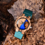 Wooden watch with blue dial and teal strap resting on tree bark