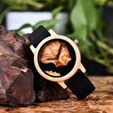 Wooden watch with wood grain patterned dial and dark case on tree bark