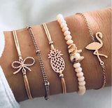 Pink bead bracelet stack with gold bow bangle and openwork disc charm on a wrist