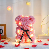 Pink rose flower teddy bear with black satin bow and warm LED string lights