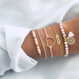 Pink bead and silver chain bracelet stack with heart charm worn on a wrist