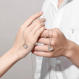Two hands clasped together each wearing a silver prince and fox pendant necklace