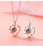 Matching heart projection pendant necklace and earrings displayed on pink background