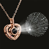 Rose gold heart locket pendant projecting I love you text in multiple languages on black background