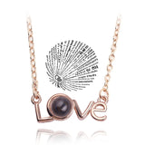 Rose gold love script pendant necklace paired with a round projection charm