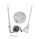 Silver love script pendant necklace paired with a round projection charm