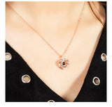 Woman wearing a rose gold heart projection pendant necklace with black top