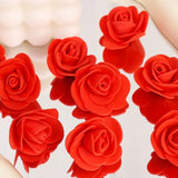 Loose red artificial foam roses arranged on a white surface