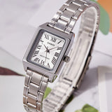 Casio tonneau watch with white Roman numeral dial shown on a surface with greenery
