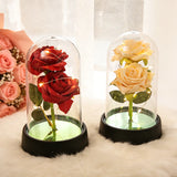 Red foil rose dome displayed beside pink gift box on a warm brown surface