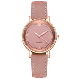 Angled rose gold watch with pink dial and pink suede strap on white background