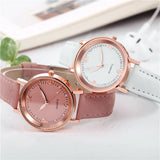 Pink dial rose gold watch styled beside dried flowers and a pale notebook