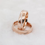 Rose gold couple wedding rings with crystal line design shown at an angled close up