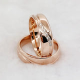 Rose gold couple wedding rings with a diagonal crystal line design on white fur background