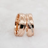 Rose gold couple wedding rings with crystal line design leaning against each other