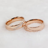 Rose gold couple wedding rings with crystal line design standing side by side