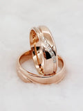Rose gold couple wedding rings with crystal line design standing close together