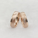 Rose gold couple wedding rings with crystal line design overlapping on white background