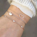 Silver bracelet stack with small charms and fine chains worn on a wrist