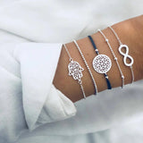 Silver bracelet stack with infinity symbol and openwork disc charms on a wrist